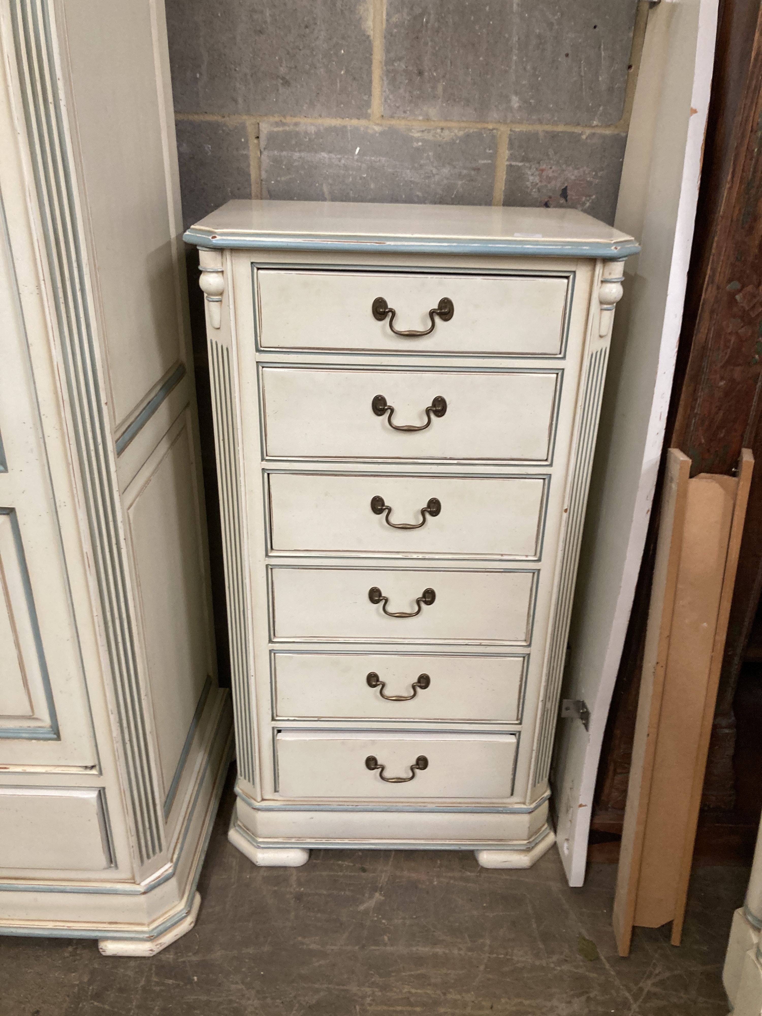 A French provincial style bedroom suite, cream painted, with blue line edging, consisting:- a two door wardrobe, four drawer chest, single bedstead and a tall chest of six drawers, wardrobe W.126cm D.61cm H.202cm
